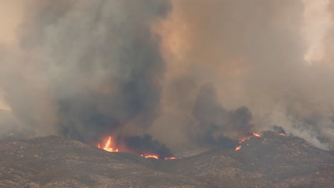 aerial view of a massive wildfire in mountains with dense puffs of smoke covering the sky in hemet, california - 6 september 2022