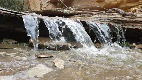 small-waterfall-from-mountain-spring-water-stream-running-down-huge-sandstone-slabs-of-rock-with-green-moss,-algae---crystal-clear-drinking-water,-meditation-tranquil-and-peaceful-calming-nature