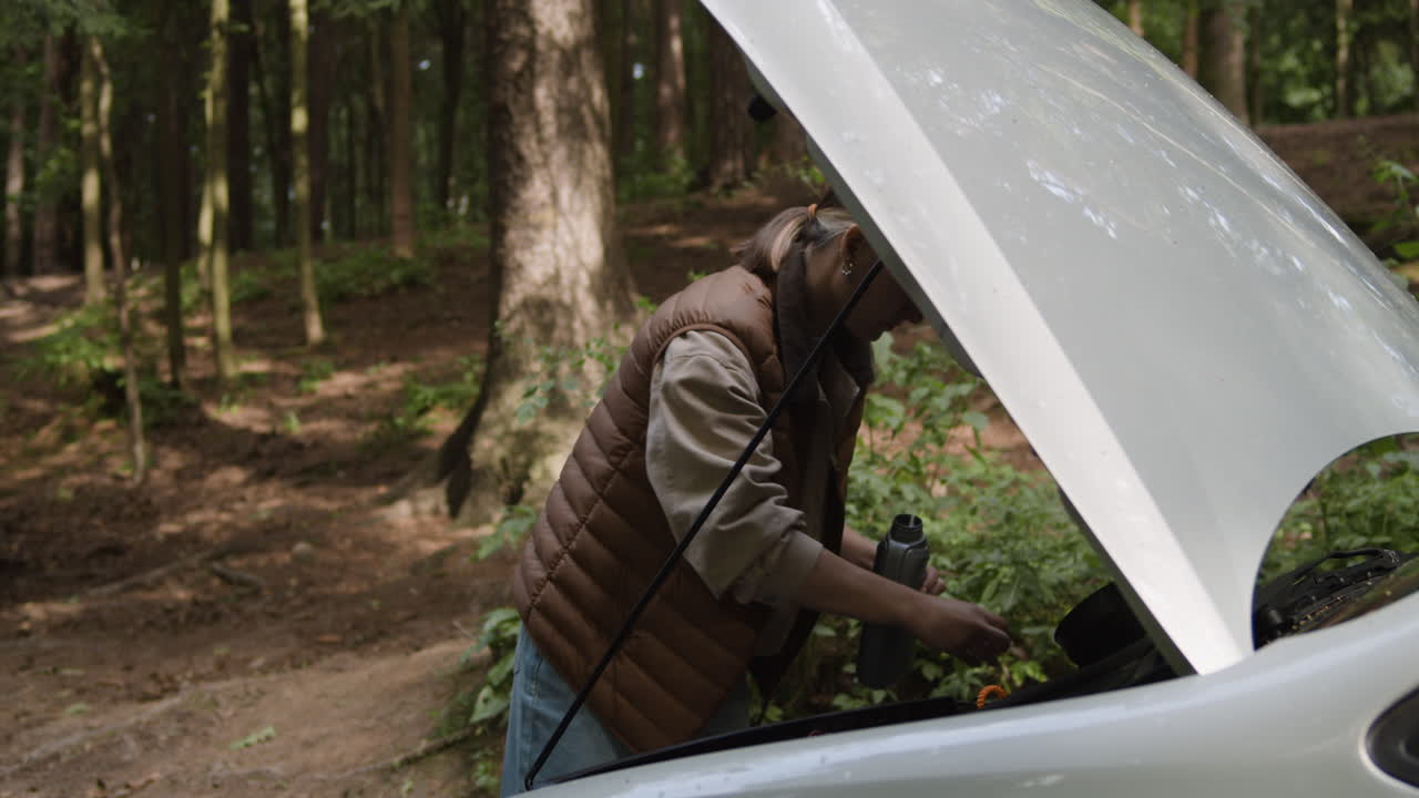 Woman Repairing Car in Forest