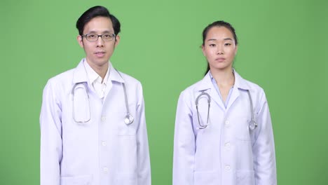 Young Asian couple doctors giving handshake together