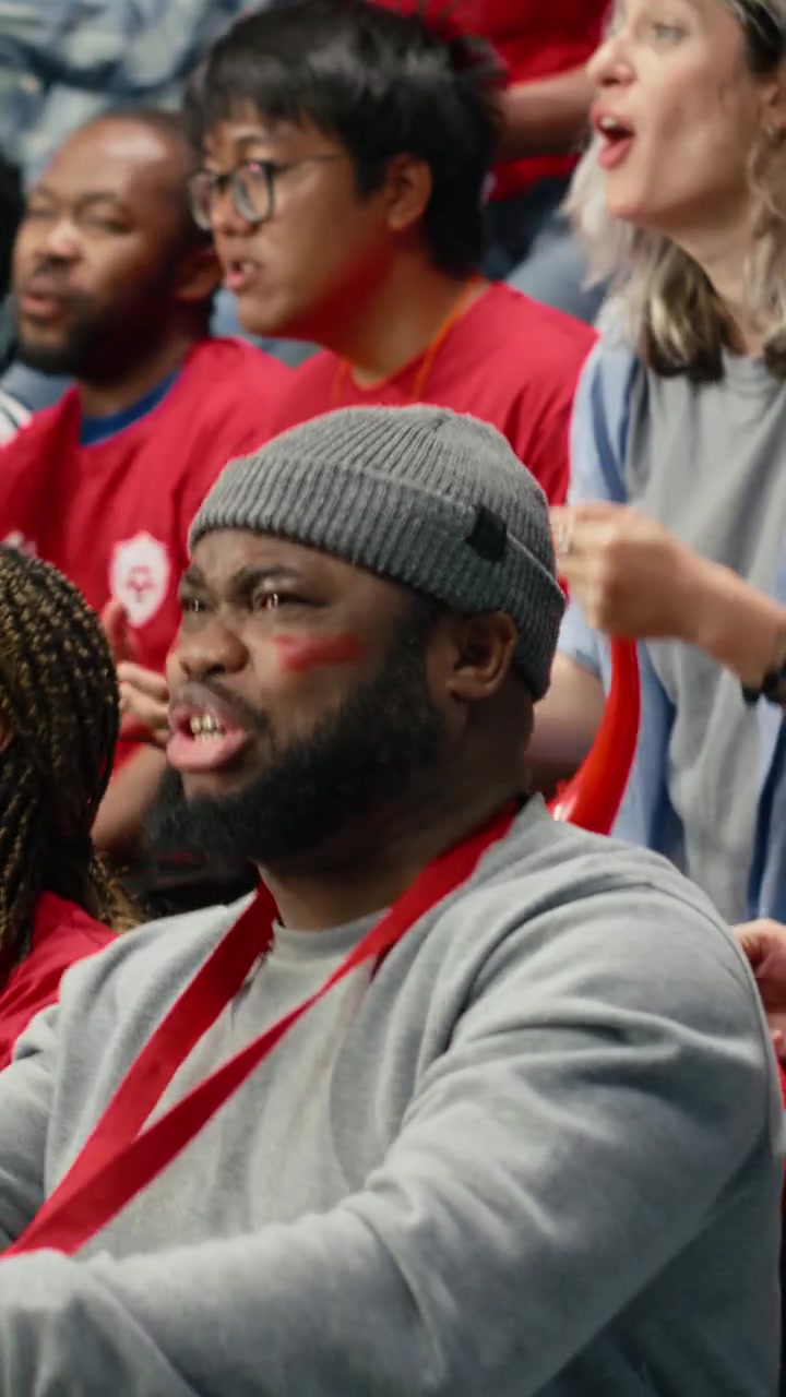Vertical Video Red football supporters watching intense live soccer match from packed stadium