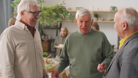 positive senior men chatting on home dinner party