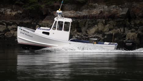 fishing boat cuts across calm water with white wash wake spreading in slow motion on side