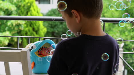 toma en cámara lenta de un niño griego jugando con una máquina de pompas de jabón en el balcón
