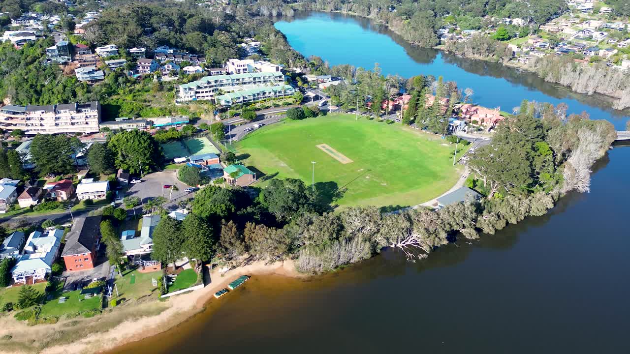 Drone aerial pan landscape of Avoca Beach community sports fields at Heazlett Park with surrounding river lagoon system, local town housing and coastline Central Coast Australia travel holidays