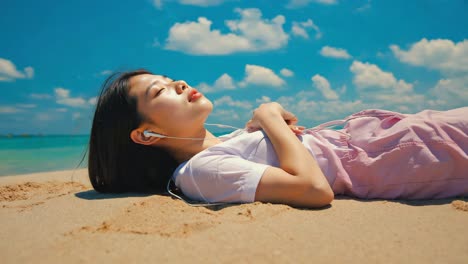 young woman relaxing on a sunny beach with earphones