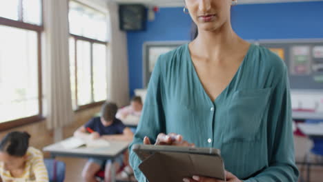 smiling teacher in classroom, students studying at desks in background
