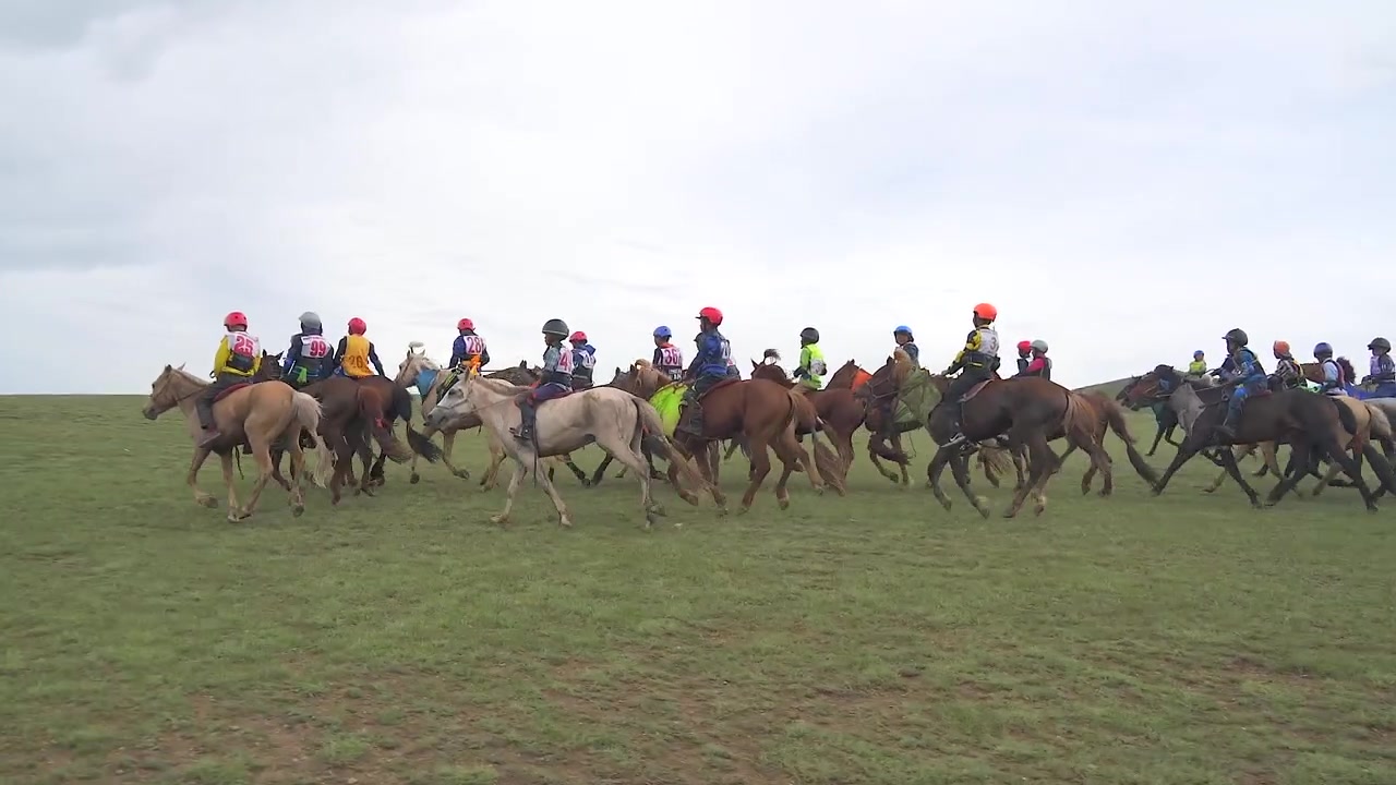 Gruppe af unge jockeys ridende på heste over den mongolske steppe