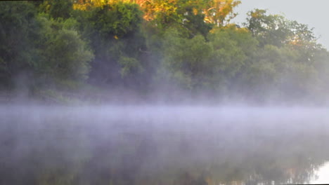 niebla y niebla moviéndose sobre un río río abajo por la mañana