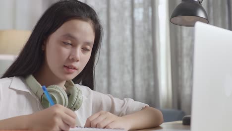 teenage girl studying at a desk with headphones