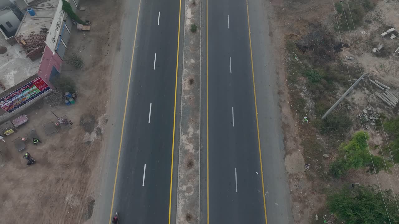 disparo hacia atrás de una autopista con vehículos que pasan con una industria a su lado en punjab, pakistán