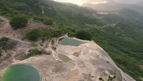 Rotating-aerial-of-Hierve-el-Agua,-which-translates-to-"the-water-boils"---series-of-stunning-mineral-laden-rock-formations-that-resemble-cascading-waterfalls,-Mexico