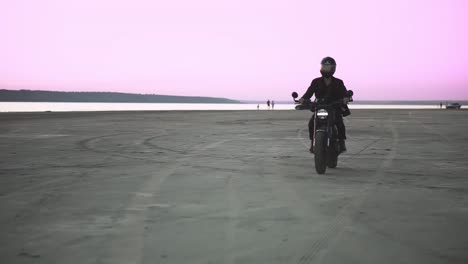 front view of unrecognizable biker in helmet and jacket, man is riding at sport motorbike. wind blowing, water front