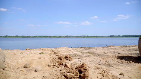 Arena-Y-Piedras-Enormes-En-La-Orilla-Del-Lago-Cerca-Del-Pueblo.-Las-Mariposas-Vuelan-Cerca-Del-Lago