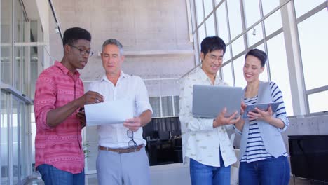 multi-ethnic business people discussing over document and laptop in modern office 4k