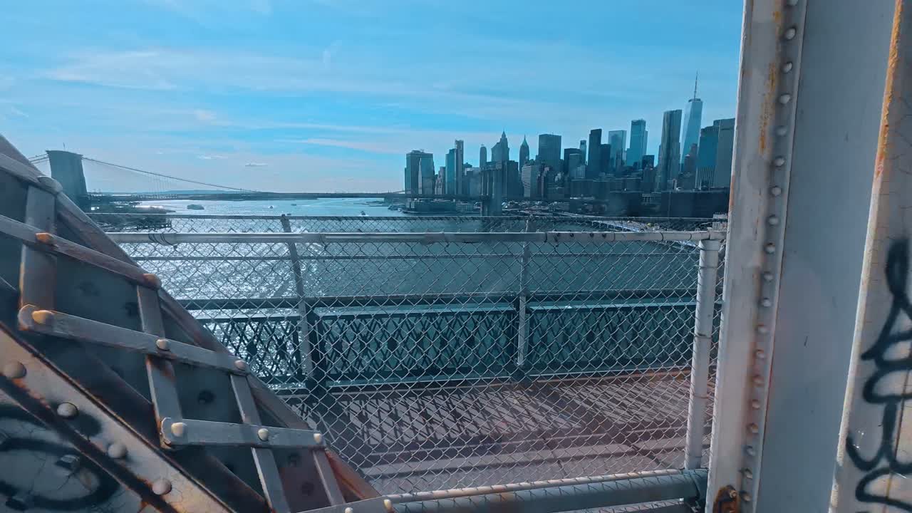 Nova Iorque, EUA, 7 de agosto de 2025: Horizonte do distrito financeiro de Nova Iorque através da estrutura de uma ponte. Vista da orla dos arranha-céus de Manhattan e do East River emoldurada por estruturas de ponte de metal industrial enferrujado.