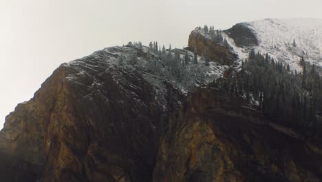 Mountain-rock-clif-with-light-snow-and-pine-trees-close-up