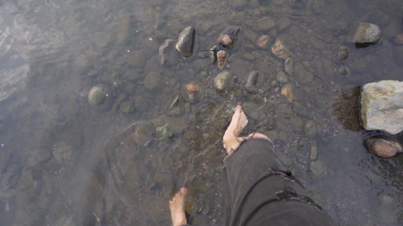 에콰도르 테나에서 화창한 날 바위가 많은 미사우알리 강을 맨발로 걷는 백인 남자의 슬로우 모션