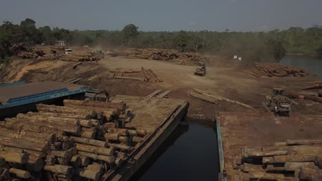 tractores cargadores apilando troncos de la selva amazónica en barcazas - paralaje aéreo