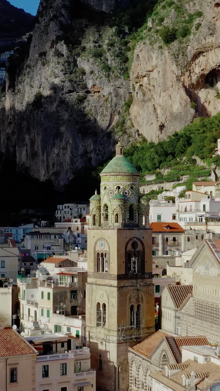 Volando hacia la Catedral de San Andrés Apóstol en la ciudad de Amalfi. Vista de dron vertical de la arquitectura italiana histórica en la Costa Amalfitana bajo el sol del atardecer