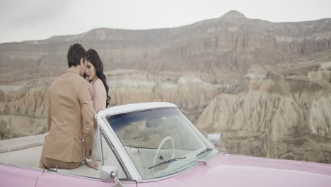 couple in vintage pink convertible car amidst stunning mountains