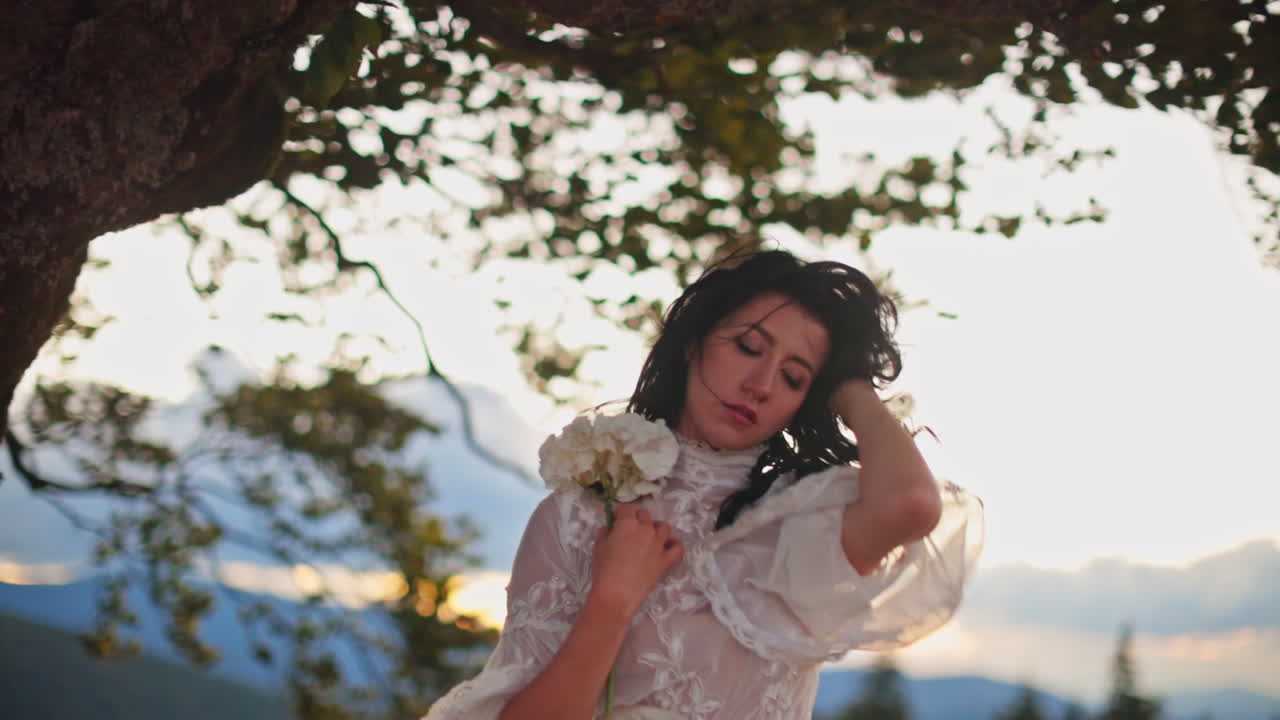 Woman in a White Dress by a Tree at Sunset