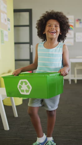 video vertical del retrato de un escolar afroamericano feliz con una caja de reciclaje