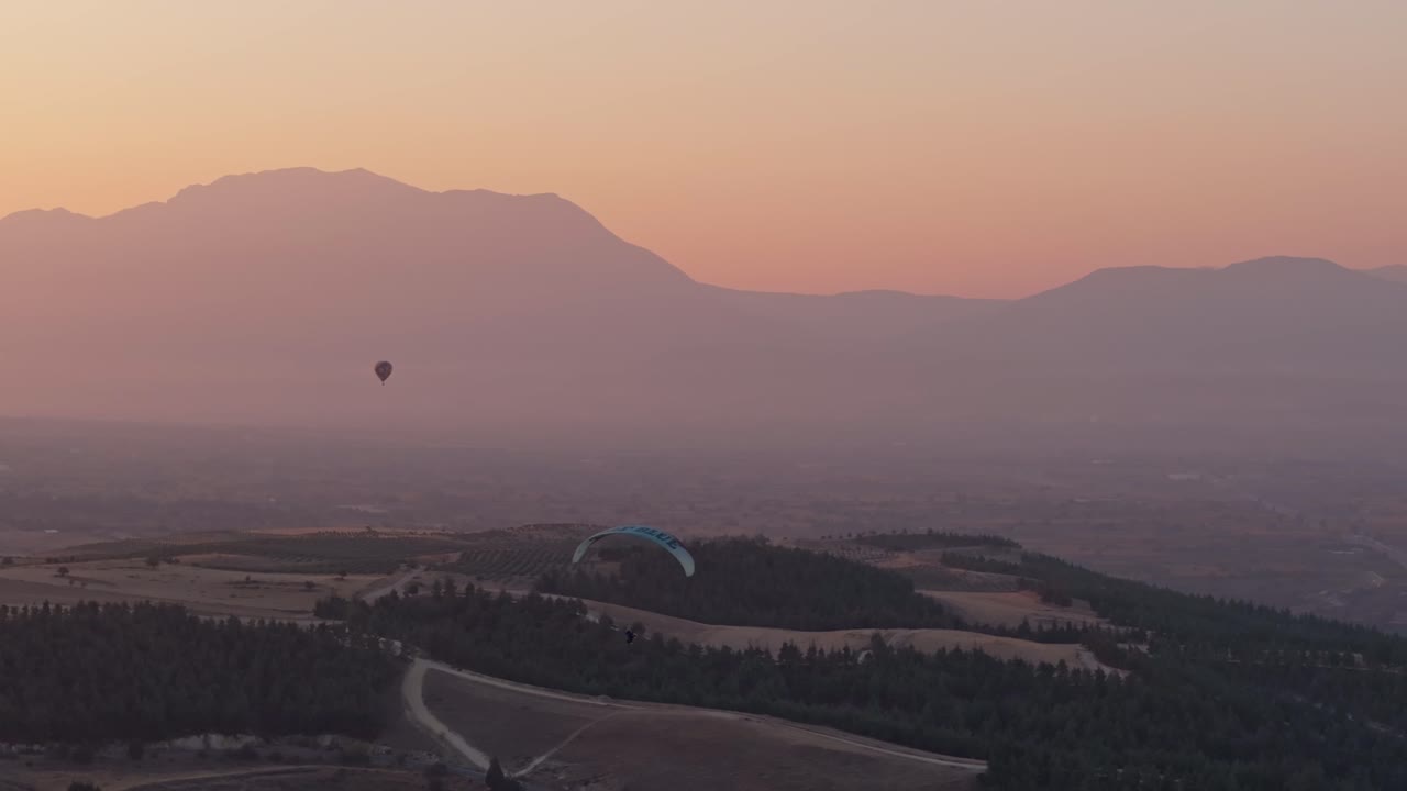 Parapendii che planano sopra le terrazze di Pamukkale all'alba in Turchia.