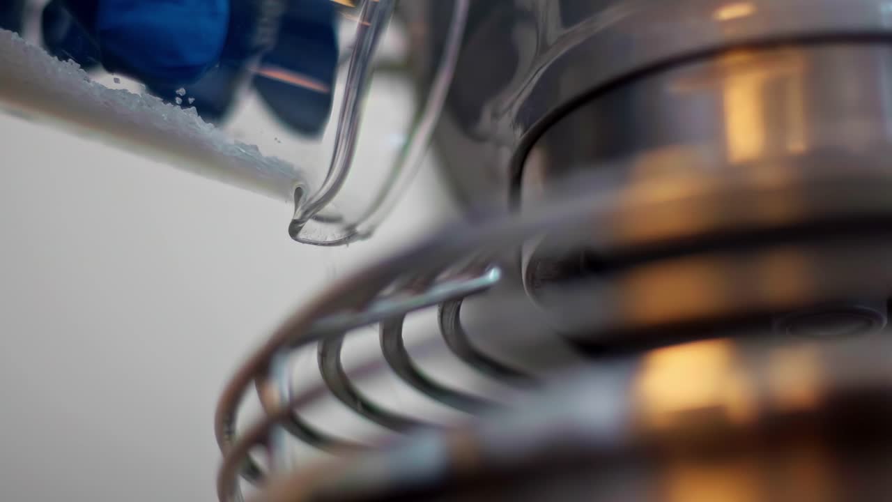 Close-up of white granules poured from container into laboratory device with visible heating element