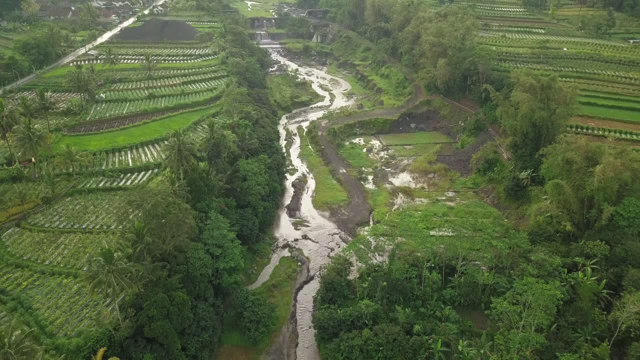fotografía aérea del canal del río que fluye entre la plantación de verduras en java central, indonesia