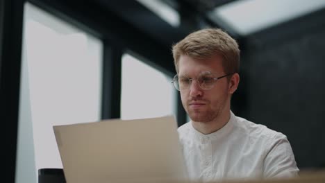 persona inteligente está trabajando en una empresa de tecnología de la información, el hombre está usando la computadora portátil para crear programas de software o videojuegos y aplicaciones