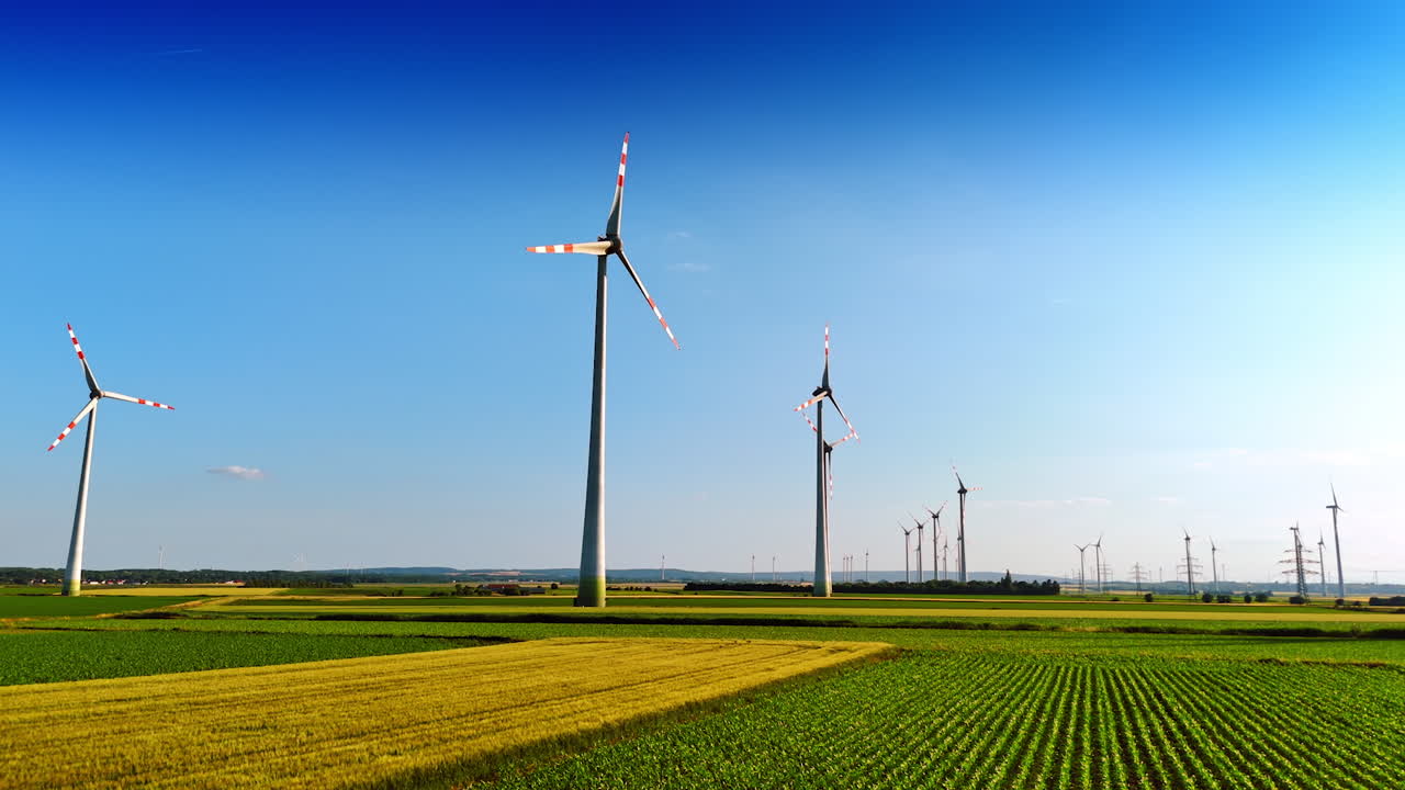 Wind turbines in fields. Wind turbines turn gracefully in a vibrant green field under a clear blue sky during daytime