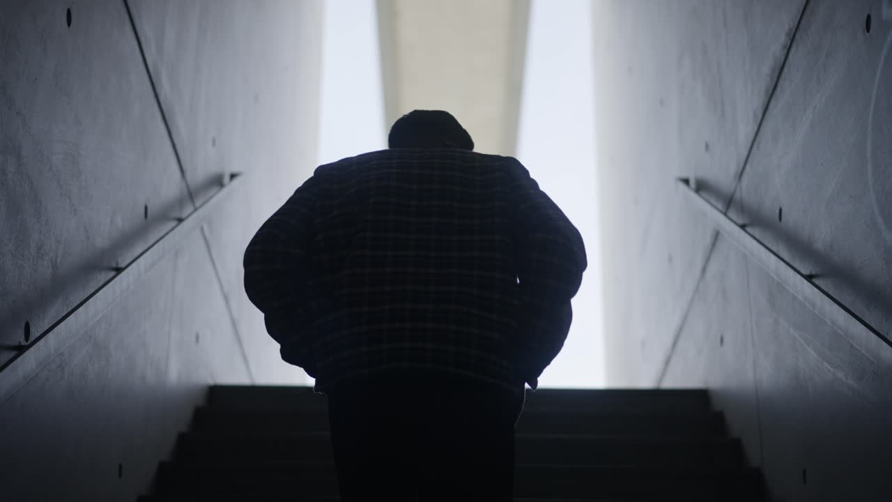 Follow Man silhouette wallking up staircase with concrete walls, Slow motion