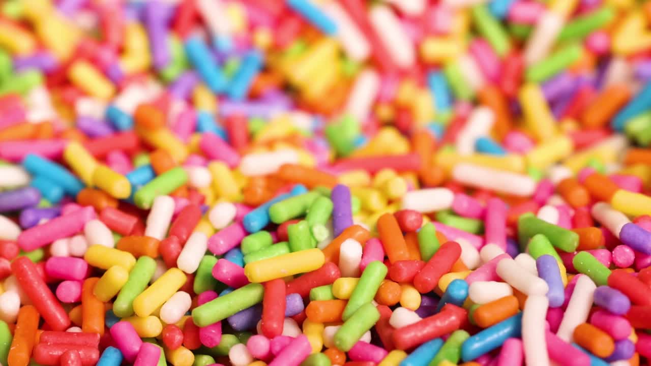 A detailed view of vibrant, multicolored sprinkles with a metal spoon partially visible.