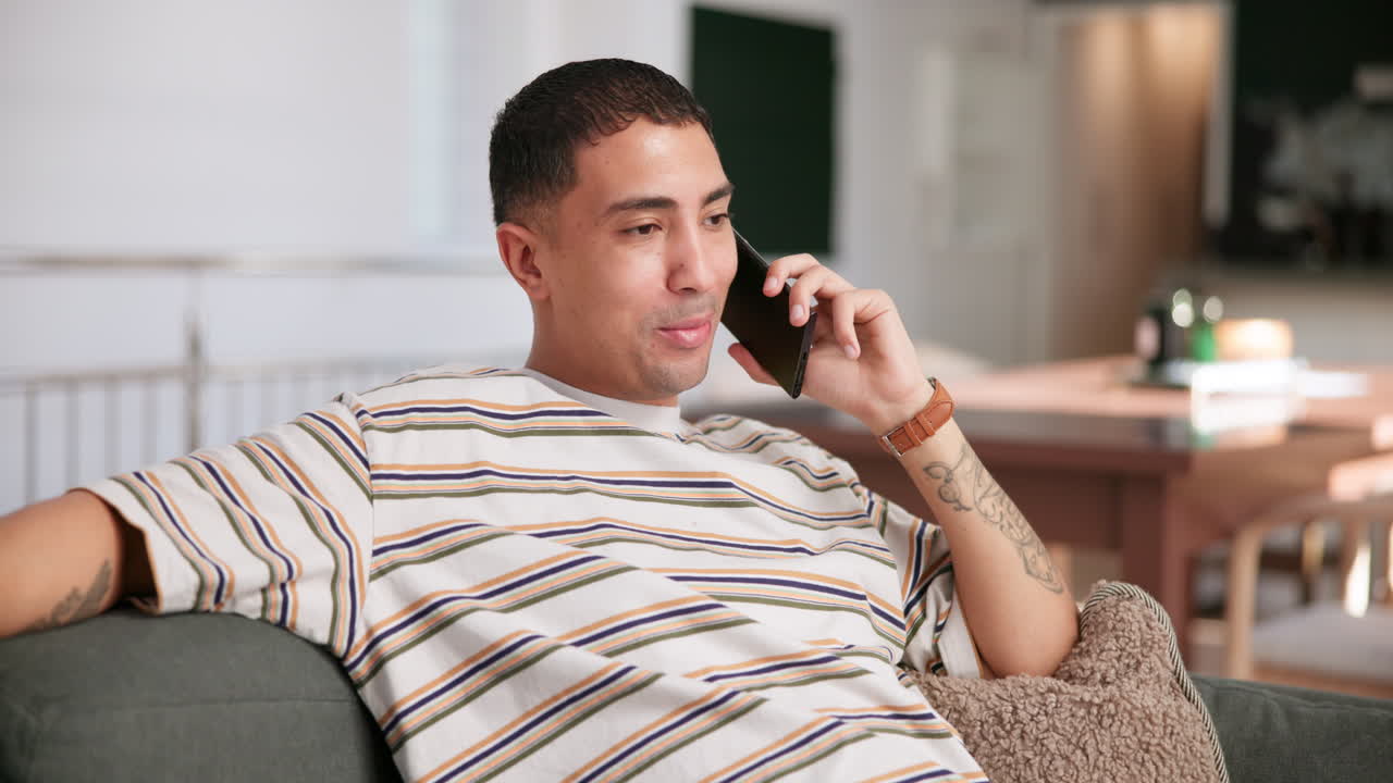 소파에 앉아서 전화로 얘기하는 남자