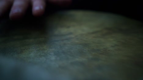 Close-up-of-person-with-traditional-medieval-costume-playing-on-old-leather-drum-in-slow-motion