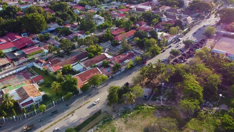 aerial drone revealing panorama view of capital dili, timor leste landscape of red roofed houses, businesses and green trees with rugged hills in distance, southeast asia