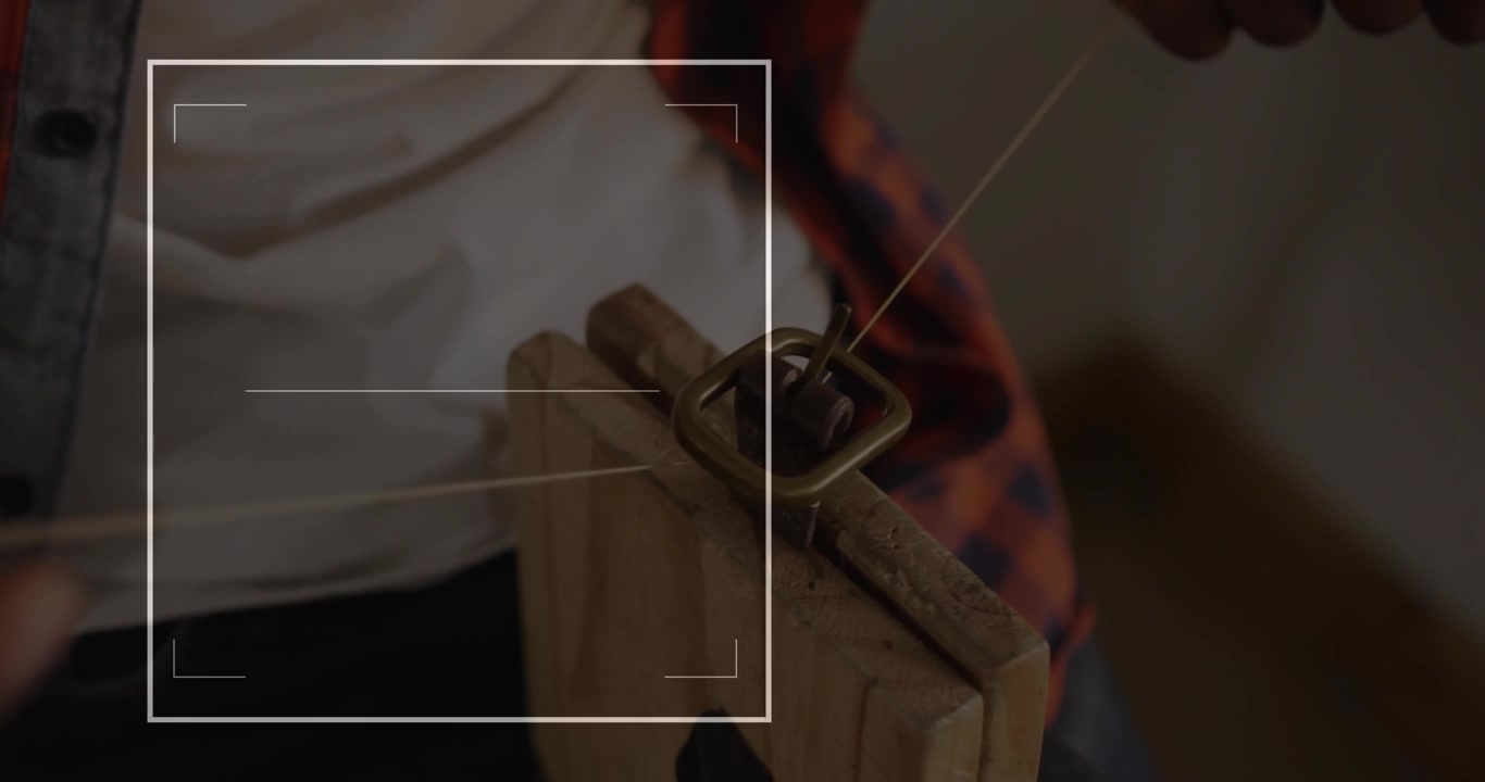 Artigiano che fissa una fibbia in una morsa, infilando un cordino e avviando una sovrapposizione tecnologica che riempie una barra di avanzamento