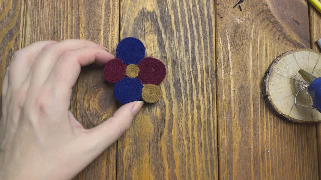 Women's hands demonstrate a felt brooch.