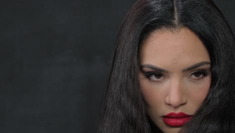 a model is applying mascara with a stylish modern look, showcasing bold red lips and eyecatching statement earrings