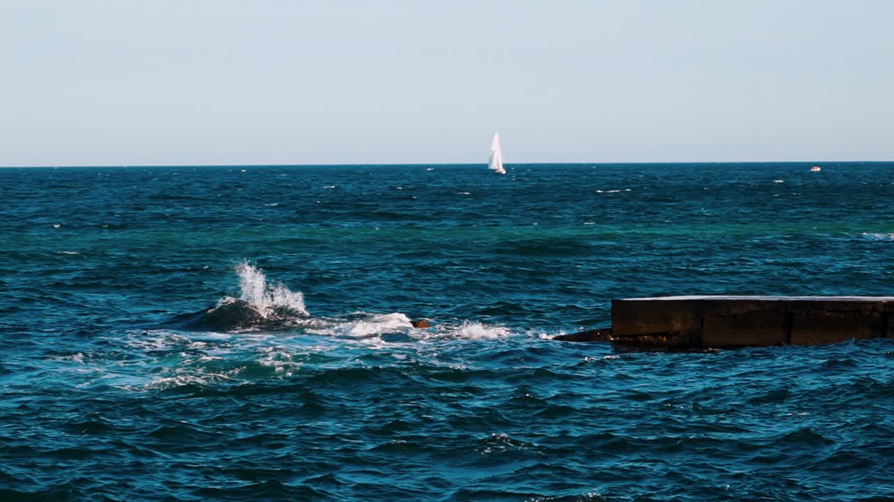 Breathtaking view on the water motion in the sea. Blue sea water background. White sail floating alone on the water surface. Slow motion.