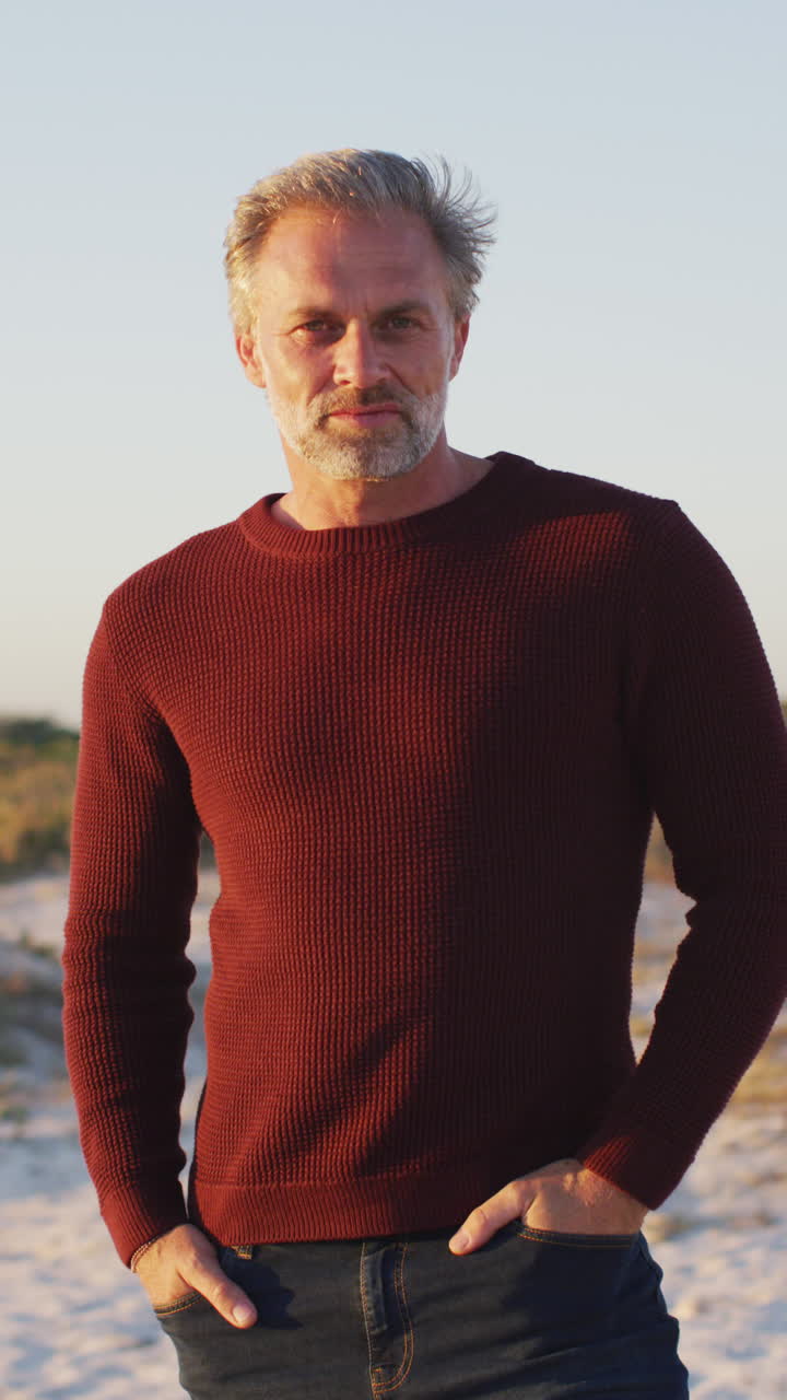 retrato de video vertical de un hombre caucásico sonriente en la playa, disfrutando del tiempo libre