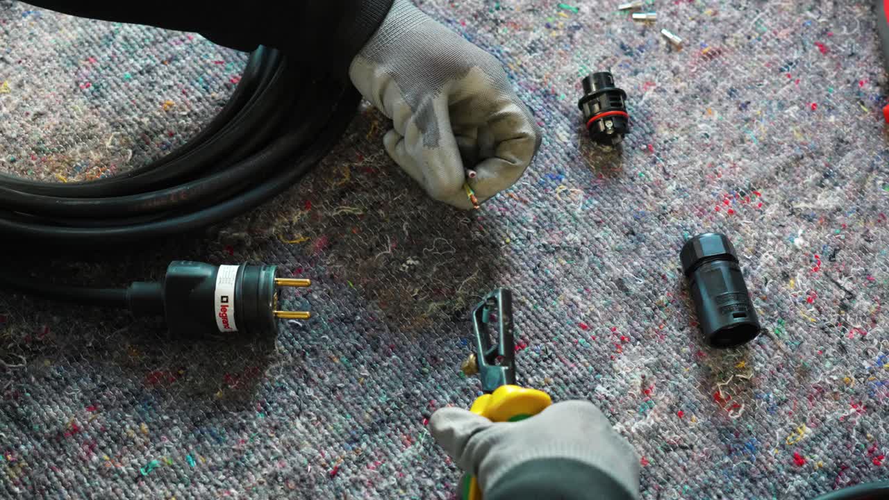 Static shot of a electrician using wire strippers to install new electrical cables