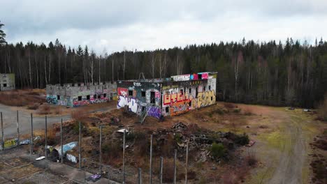 aerial view of abandoned building with graffiti in front of forest trees in sweden