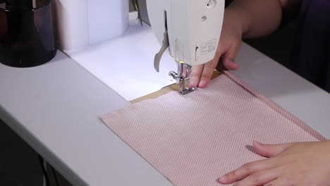 máquina de coser que se utiliza para coser todo el lado de la tela de color rosa y blanco