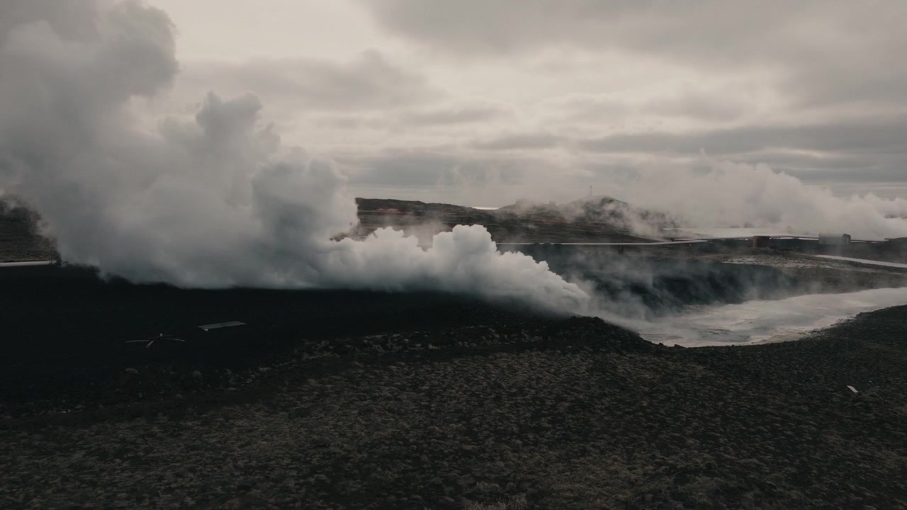 Vista aerea del vapore geotermico che si innalza su un campo lavico scuro a Reykjanes, Islanda