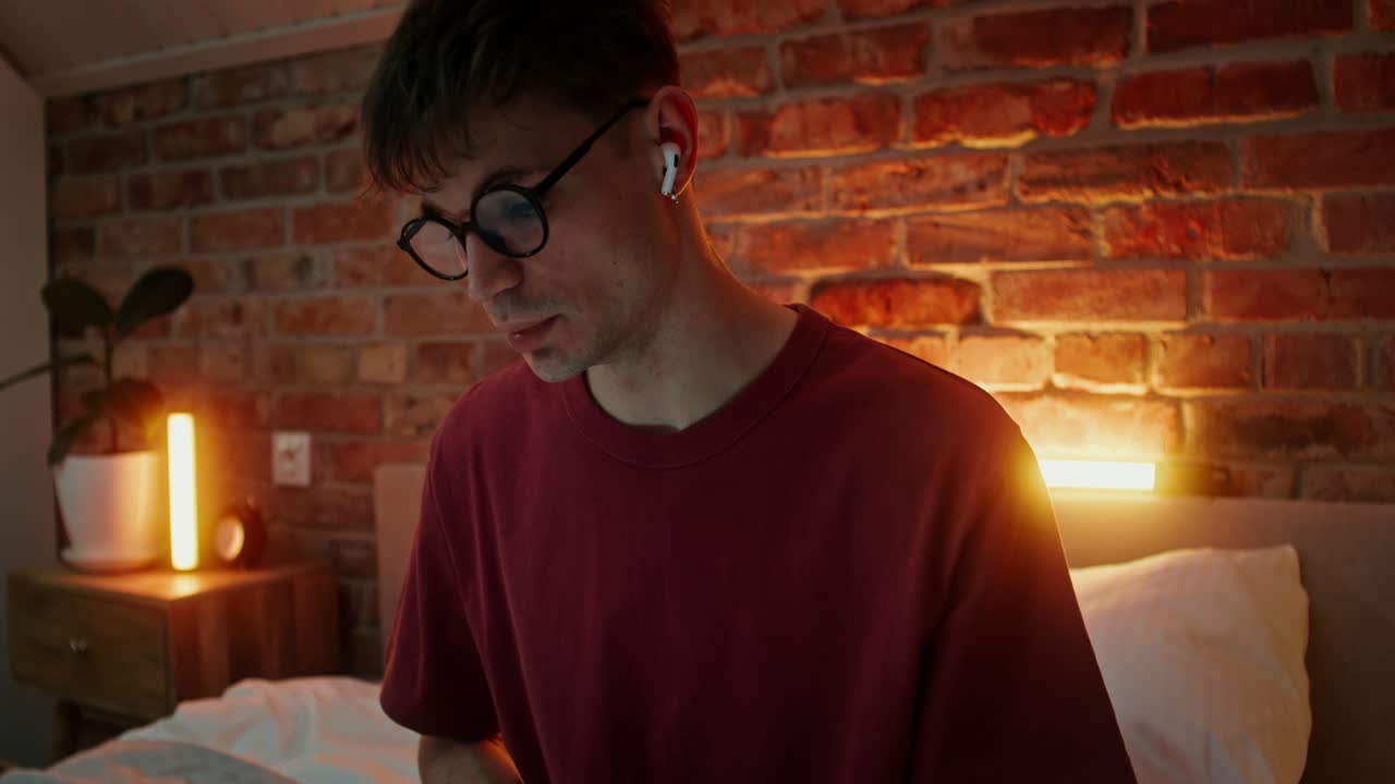 젊은 남자가 침실에서 노트북으로 일하고 있다