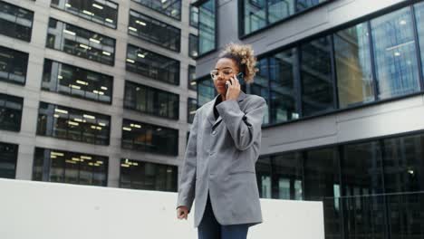 young woman on phone in front of modern city buildings