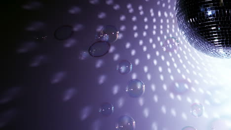 shiny disco ball revolving with floating bubbles close up