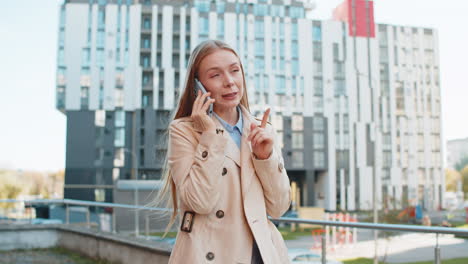mature caucasian businesswoman having remote conversation on smartphone on downtown city street
